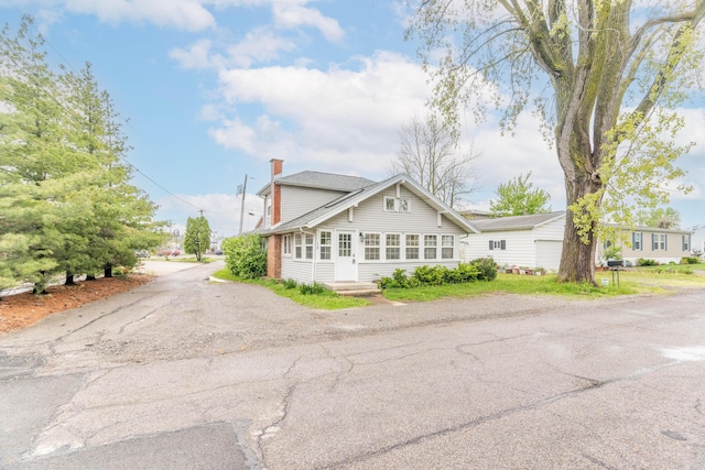 view of front of property with a chimney and asphalt driveway