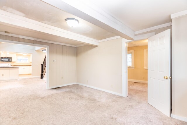 below grade area featuring light carpet and baseboards