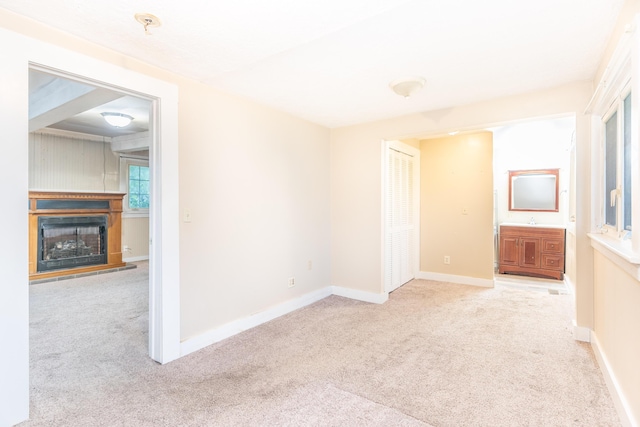 spare room with carpet, a fireplace with raised hearth, baseboards, and a sink