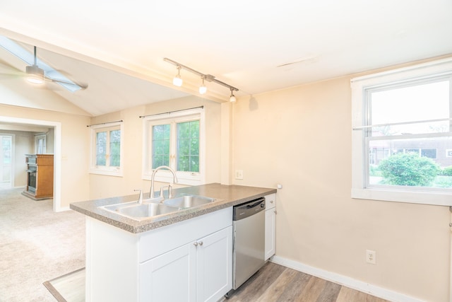 kitchen featuring stainless steel dishwasher, a sink, baseboards, white cabinets, and plenty of natural light
