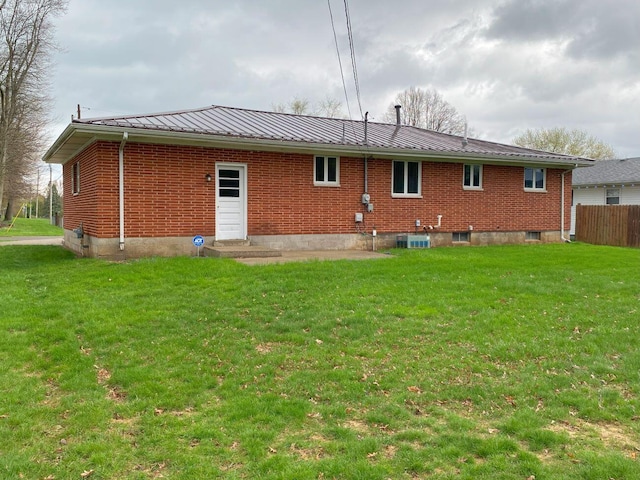 rear view of house with a lawn, brick siding, and metal roof