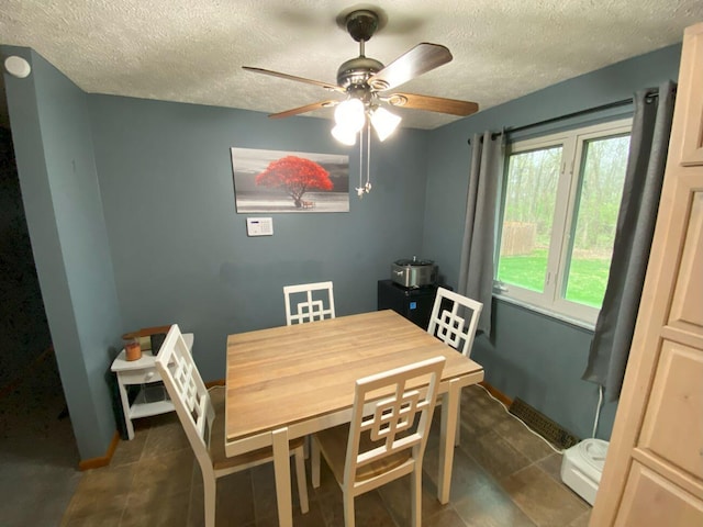 dining room featuring dark tile patterned floors, a textured ceiling, a ceiling fan, and baseboards