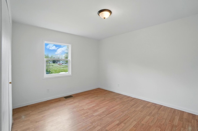 empty room with baseboards, visible vents, and light wood-style floors