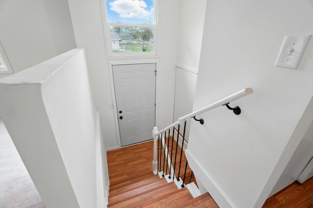 stairway with baseboards, wood finished floors, and plenty of natural light