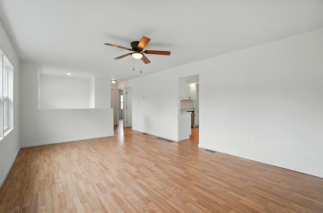 unfurnished living room featuring visible vents, a ceiling fan, light wood-style flooring, and baseboards