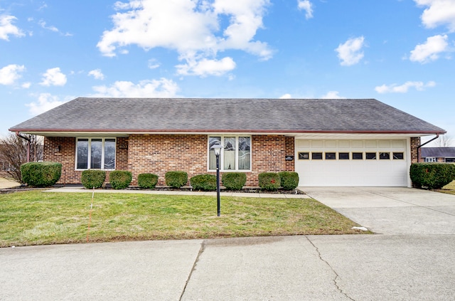 ranch-style house with a garage, a shingled roof, concrete driveway, a front lawn, and brick siding