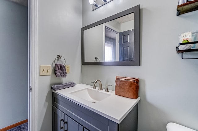 half bath with toilet, vanity, and baseboards