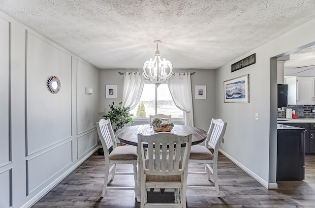 dining space featuring baseboards, a textured ceiling, a chandelier, and dark wood-style flooring