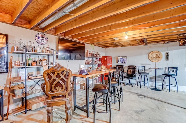 bar with a dry bar, concrete floors, and concrete block wall