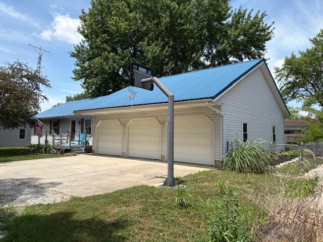 6645 Oak Dr, Celina, OH 45822 - view of side of property featuring a garage, concrete driveway, a porch, and a metal roof