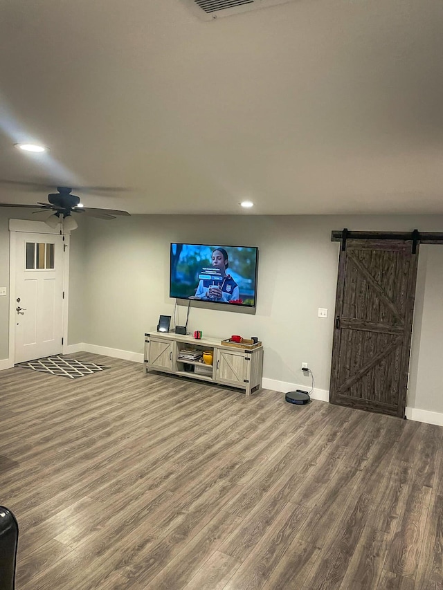 living area featuring a barn door, recessed lighting, wood finished floors, a ceiling fan, and baseboards