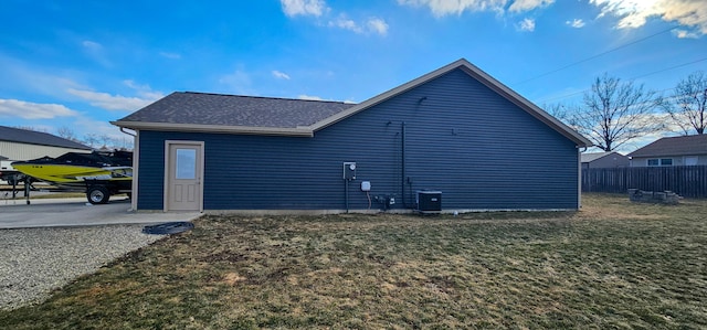 back of property with a shingled roof, cooling unit, fence, and a lawn