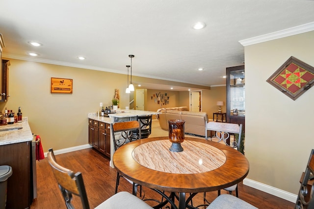 dining room featuring ornamental molding, baseboards, bar area, and dark wood-style floors
