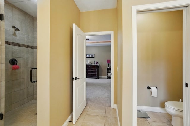 bathroom with a shower stall, tile patterned floors, baseboards, and toilet