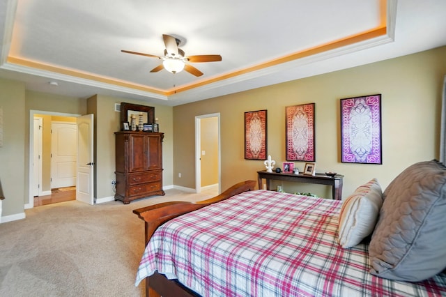 carpeted bedroom with a tray ceiling, baseboards, and ceiling fan