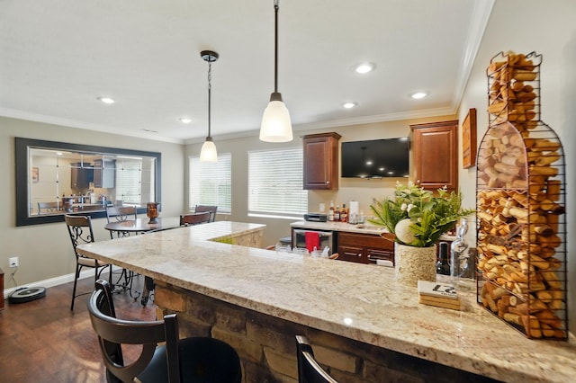 kitchen featuring dark wood-style flooring, a kitchen breakfast bar, ornamental molding, a peninsula, and light stone countertops