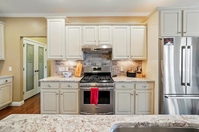 kitchen featuring stainless steel appliances, under cabinet range hood, dark wood-type flooring, and backsplash