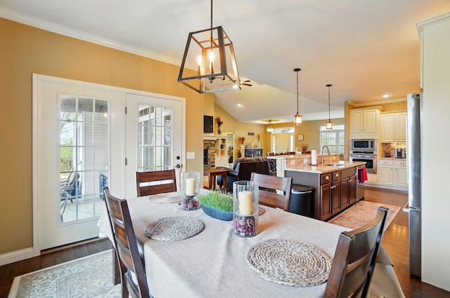 dining space featuring baseboards, a chandelier, crown molding, wood finished floors, and lofted ceiling