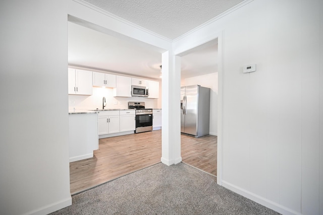 8095 N Lena-Palestine Rd, Conover, OH 45317 - kitchen featuring appliances with stainless steel finishes, white cabinetry, crown molding, light countertops, and light colored carpet