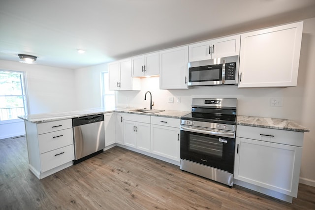 8095 N Lena-Palestine Rd, Conover, OH 45317 - kitchen featuring appliances with stainless steel finishes, wood finished floors, a peninsula, white cabinetry, and light stone countertops