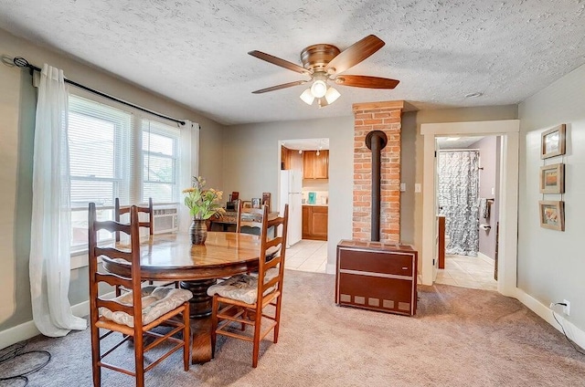 dining space with ceiling fan, a wood stove, light carpet, and a textured ceiling