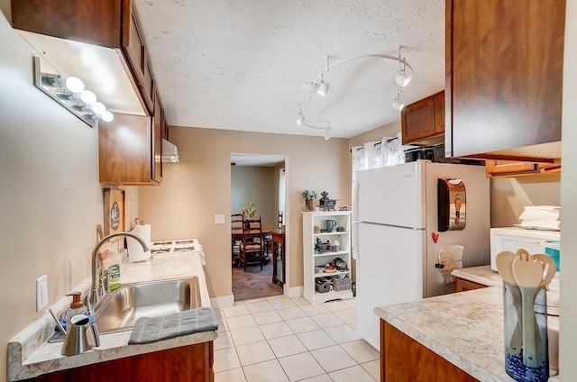 kitchen featuring a textured ceiling, sink, white fridge, and light tile patterned floors