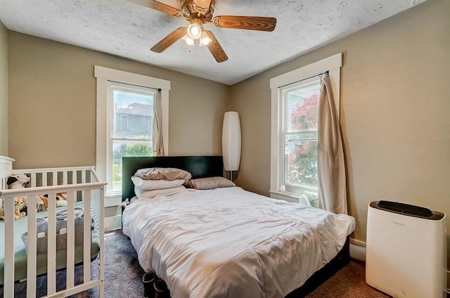 carpeted bedroom featuring multiple windows, a textured ceiling, and ceiling fan