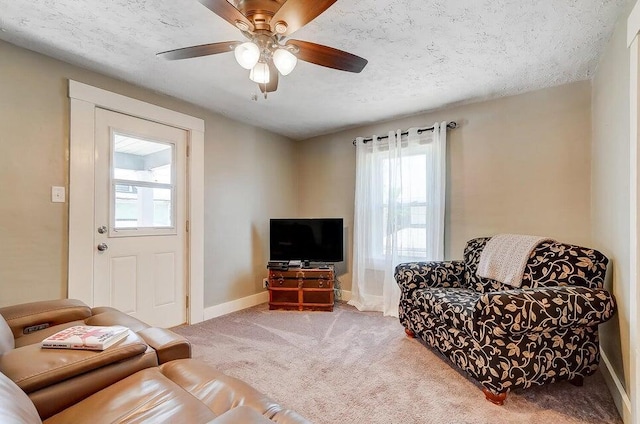 carpeted living room featuring ceiling fan and a textured ceiling