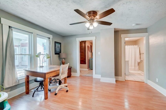 home office with ceiling fan, a textured ceiling, and light wood-type flooring