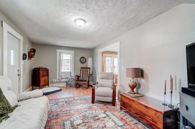 living room featuring cooling unit, light hardwood / wood-style floors, and a textured ceiling