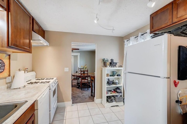 kitchen featuring sink, wall chimney range hood, white appliances, and light tile patterned floors