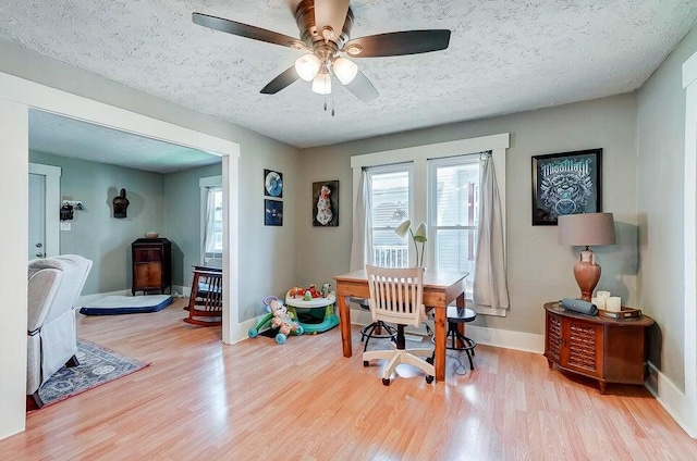 home office with ceiling fan, light hardwood / wood-style flooring, and a textured ceiling