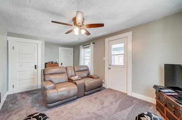 carpeted living room featuring ceiling fan and a textured ceiling