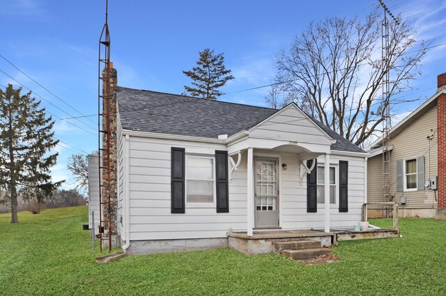 bungalow-style home with a shingled roof, a chimney, and a front lawn