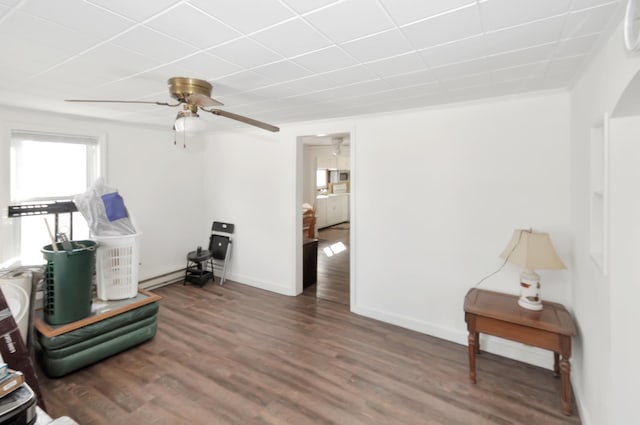 sitting room featuring dark wood-style flooring, ceiling fan, and baseboards