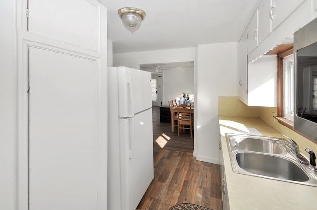 kitchen with dark wood finished floors, freestanding refrigerator, light countertops, white cabinetry, and a sink