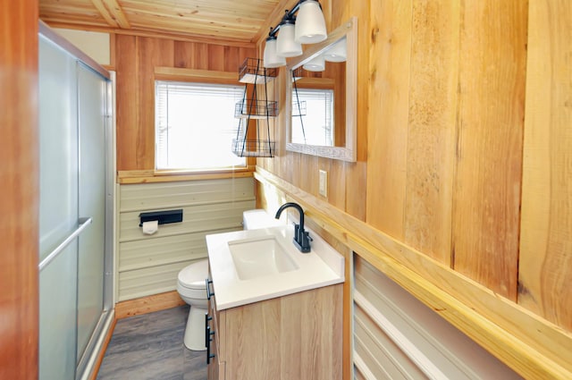 full bath featuring toilet, a stall shower, wood ceiling, wooden walls, and vanity