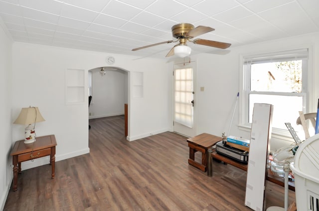 interior space with arched walkways, dark wood finished floors, plenty of natural light, and baseboards