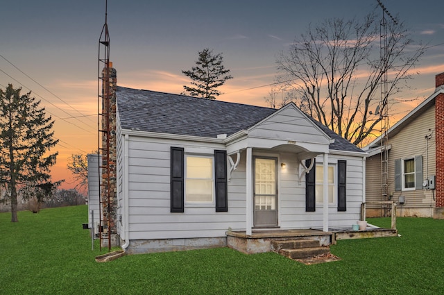 bungalow-style home with roof with shingles and a front yard