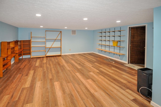 finished below grade area featuring recessed lighting, visible vents, baseboards, a textured ceiling, and wood finished floors