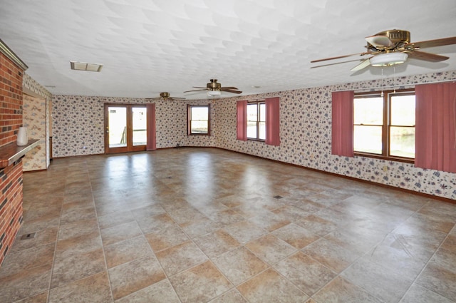 unfurnished living room featuring ceiling fan and wallpapered walls