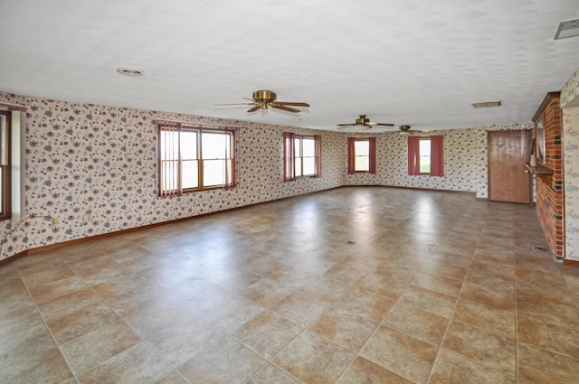 unfurnished living room featuring baseboards, wallpapered walls, and a ceiling fan