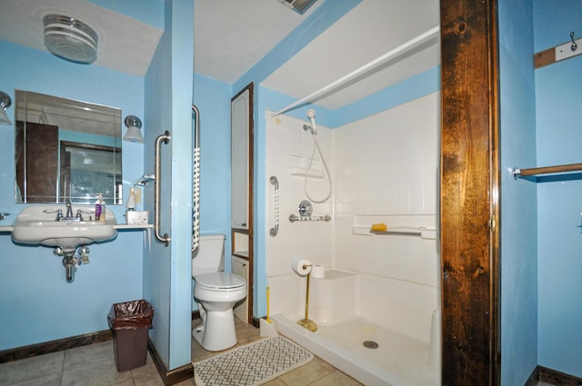 bathroom with toilet, a stall shower, tile patterned flooring, and baseboards