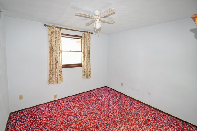 carpeted spare room with a ceiling fan and baseboards