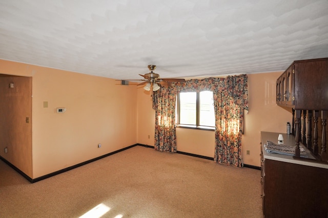 spare room featuring baseboards, ceiling fan, and light colored carpet