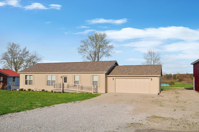 ranch-style house featuring roof with shingles, gravel driveway, a front yard, and an attached garage
