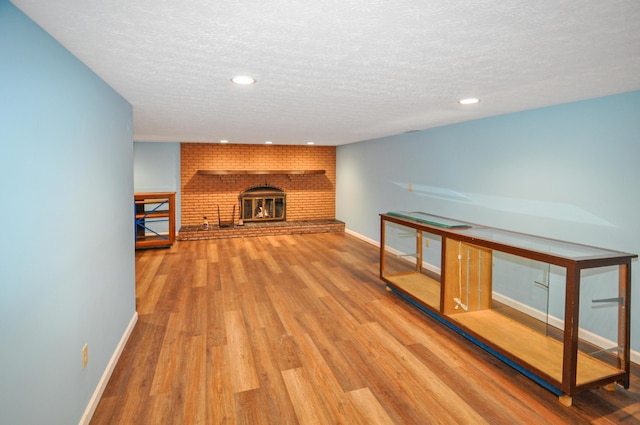 unfurnished living room featuring a textured ceiling, wood finished floors, recessed lighting, and baseboards