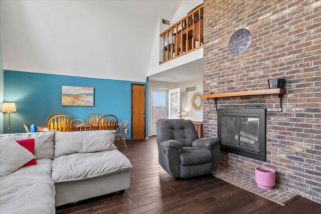 living area with hardwood / wood-style floors, a high ceiling, a fireplace, and visible vents