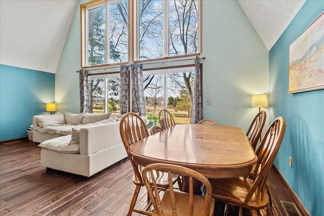 dining space featuring visible vents, baseboards, dark wood-type flooring, and high vaulted ceiling