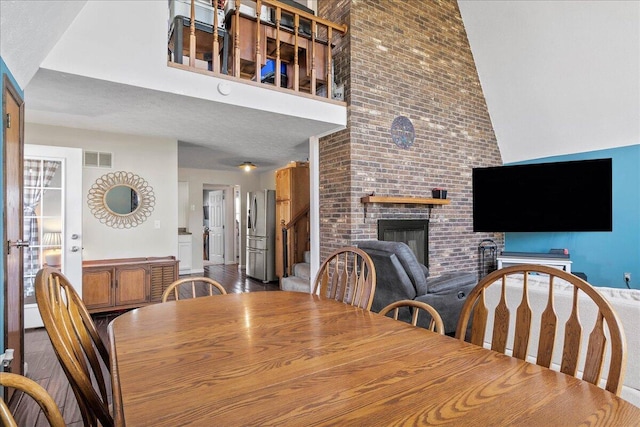 dining space featuring visible vents, a brick fireplace, and a towering ceiling